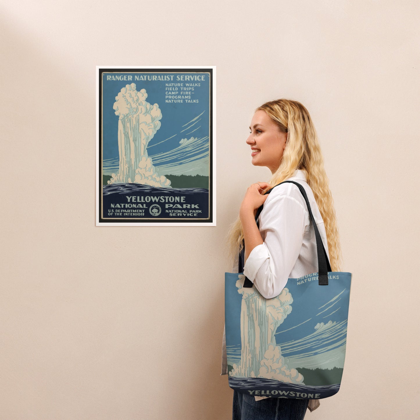 Woman holding a tote bag with Yellowstone National Park design, next to a framed poster of the same design.