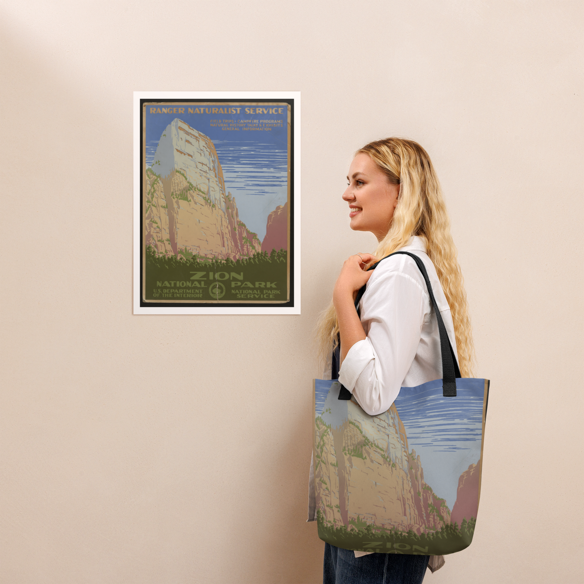 Woman holding a tote bag with a national park design, next to a framed poster of the same design.